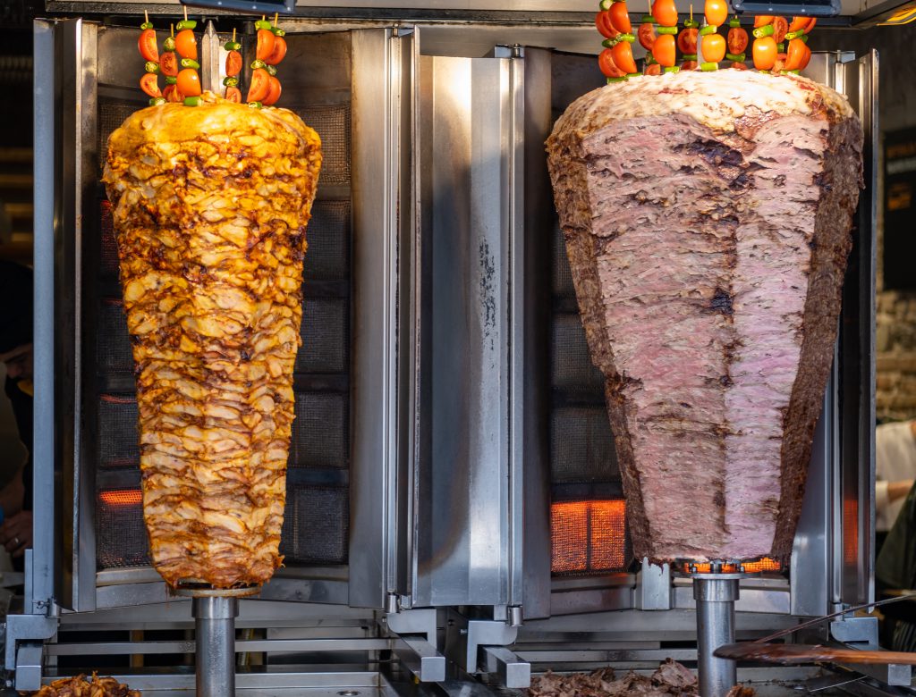Shot of appetizing marinated meat for shawarma stacked on skewers